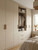A cozy bedroom interior featuring floor-to-ceiling fitted wardrobes and an open closet section elegantly wrapped in Layed Beige Linen Fabric Vinyl Wrap with matching wood hardware.