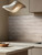 A close-up of a modern kitchen backsplash and countertop beautifully showcasing the warm, linear, earthy grain of Layed Travertine Stone Vinyl Wrap.