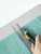 Cutting Sage Green peel and stick composite wall tile with a utility knife around an outlet