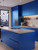A contemporary kitchen featuring flat-panel cabinets and a large center island completely transformed with Layed Matte Deep Blue Vinyl Wrap, showcasing a bold, non-reflective finish.