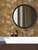 Close-up of waterproof, self-adhesive Bronze Metal hexagon tiles installed around a bathroom mirror.