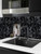 A monochromatic kitchen design featuring a matte black hexagon tile backsplash behind a dark sink and modern faucet.