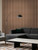 A stylish living room featuring a full-height Smoked Walnut slatted accent wall behind a dark grey sectional sofa.