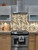 Modern kitchen featuring a luxurious brass metal herringbone peel and stick tile backsplash behind a cooker.