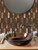 A luxurious bathroom accent wall made of metallic copper picket tiles, creating a warm, industrial aesthetic.