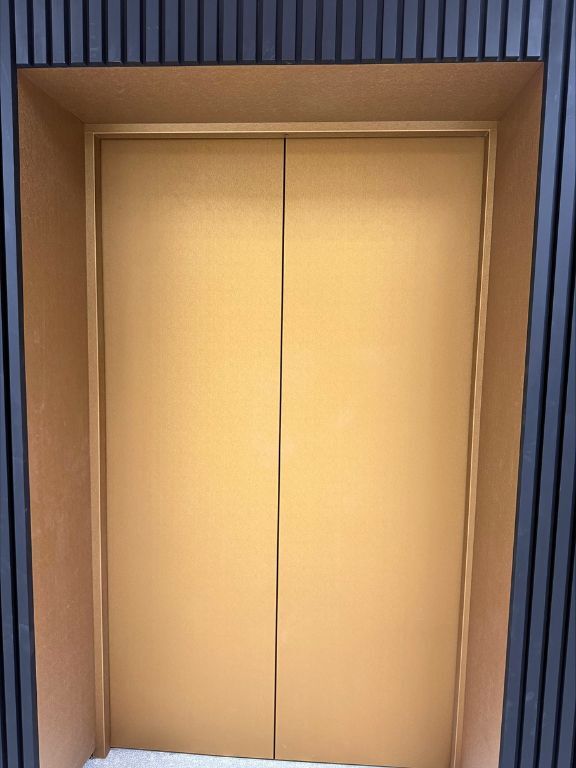 Commercial lift sliding doors and surrounds wrapped in layed Brushed Gold Interior Film.
