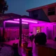 A patio pergola flooded with vibrant fuchsia light from the ColorBright™ RGB + Dynamic Tunable White IP65 LED Strip Light.