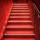 ColorBright™ Vivid Single-Color IP20 LED Strip Light illuminating indoor stair treads with a striking, intense red glow.