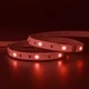 Outdoor ColorBright™ RGB 150 IP65 LED Strip lit in red, green, and blue while coiled on a dark reflective surface.