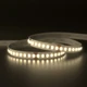 UltraBright™ Architectural IP20 LED Strip illuminated in a soft 3000K warm white glow while coiled on a reflective surface.