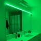 ColorBright™ RGB 300 IP20 LED Strip creating a vivid green ambient glow over a modern bathroom sink and mirror.