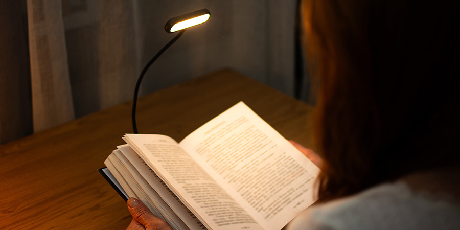 Person reading book with a clip-on book lamp
