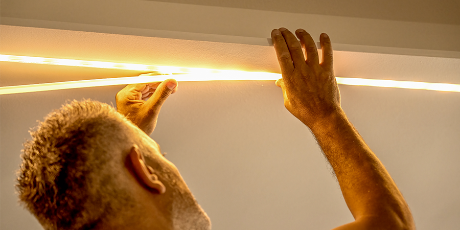 Man installing LED strip lighting project with recessed mounting channel