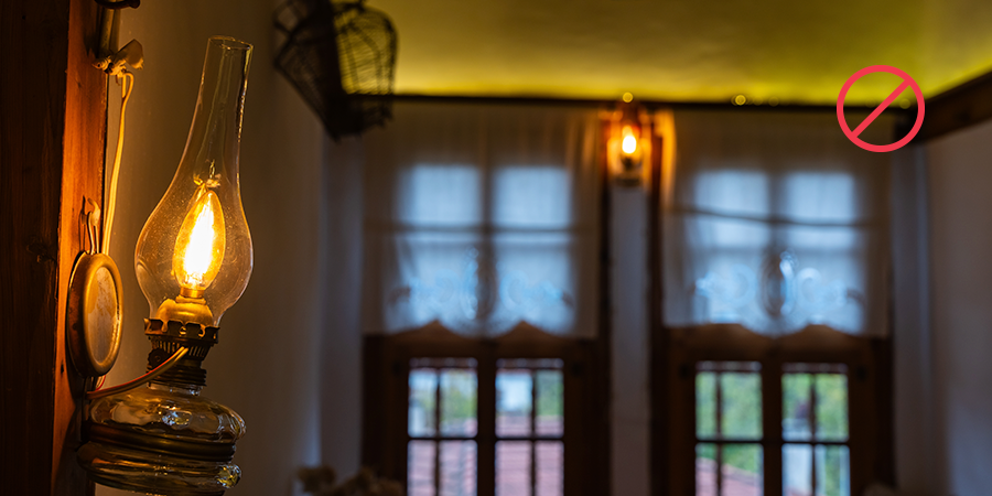 Old-style oil lamp lit indoors with a red “no” symbol