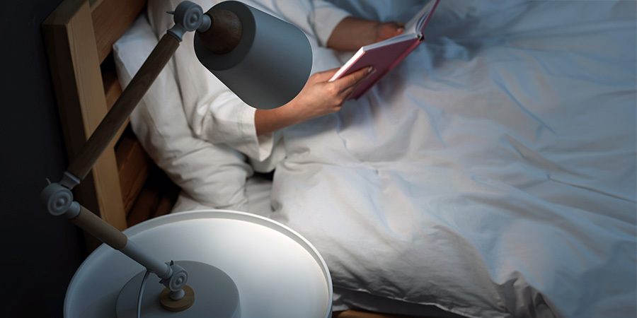 Person Reading On Bed Under Lamp Lighting