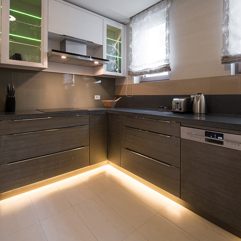 Modern kitchen with dark cabinets and warm LED lighting on toekick area