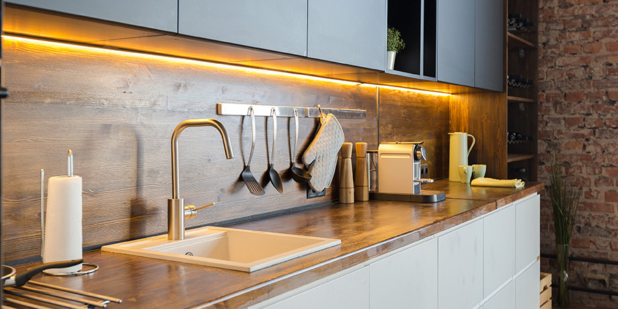 Modern kitchen with LED undercabinet lights, wood countertop and gray cabinets