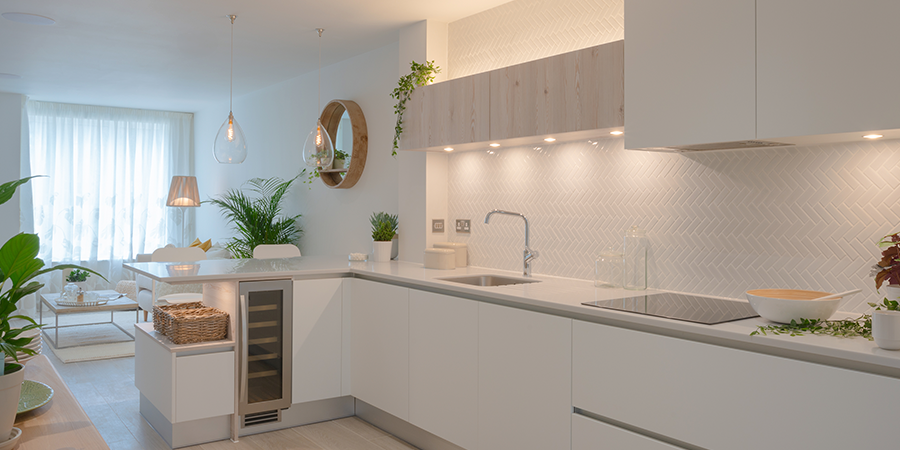 Modern kitchen with under cabinet LED puck lights illuminating white cabinets and backsplash