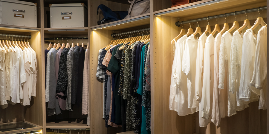 Walk in closet with white LED strip lights on the shelves, rods, and cabinets