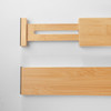 A detailed close-up of the end of a bamboo drawer divider, highlighting the non-slip grip pad and the internal spring-loaded mechanism that ensures a secure fit.
