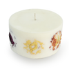 The inclusion candle is shown against a clean white background, providing a clear view of the variety of real flowers, including pink, red, and yellow blooms, embedded around its circumference.