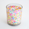 An angled view of the celebration candle in its glass jar on a white background, showing the texture and fun, festive appearance of the embedded sprinkles.