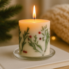 Lit fir and berry inclusion pillar candle on a clear glass tray sitting on a wooden surface