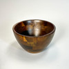 A single, empty acacia wood individual bowl viewed from a slight angle, emphasizing its smooth interior, depth, and elegant design.