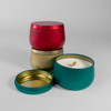 Close-up of teal and gold candle tins with lids off, showing wood wicks on white faux snow