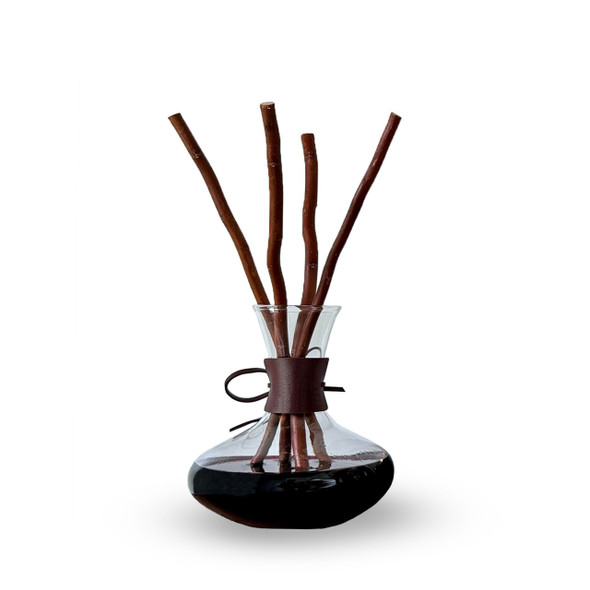 A clear, isolated product shot of the decanter reed diffuser against a plain white background, showing the full set with the glass decanter, leather wrap, and willow reeds.