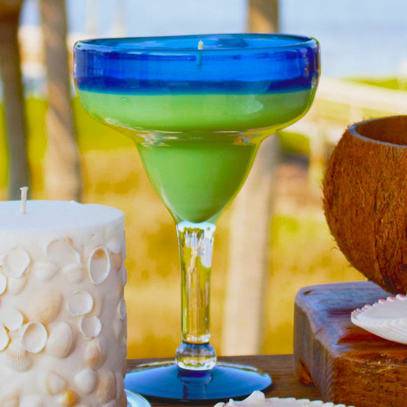 The La Playa Cocktail Candle is styled in a sunny, outdoor setting next to other candles, perfect for a summer party or patio decor.