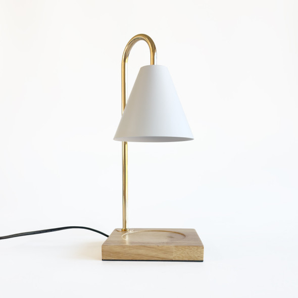 Side profile of the candle warmer on white background showing curved brass arm and conical white metal shade Side profile of the candle warmer on white background showing curved brass arm and conical white metal shade