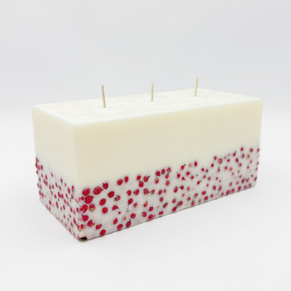 Close-up of the rectangular candle showing the vibrant red berry inclusion within the white wax. Close-up of the rectangular candle showing the vibrant red berry inclusion within the white wax.