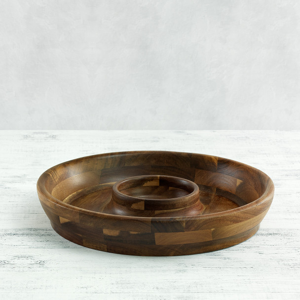 The empty acacia wood chip and dip platter is shown from a side angle, highlighting its rich end-grain construction and the built-in central bowl.