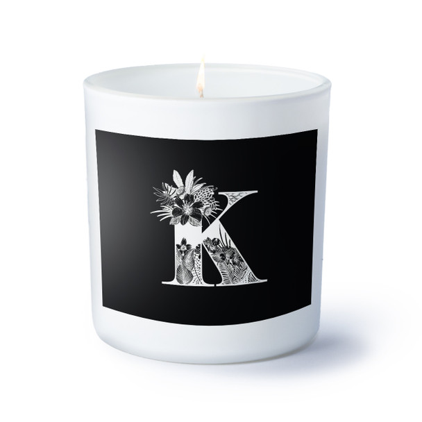 A white candle featuring a stylish black and white design of the letter K.
