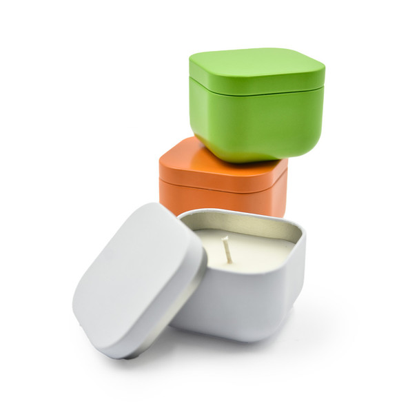 This is a duplicate of the main image, showing a styled arrangement of the three colorful, square candle tins with one opened to display the candle.