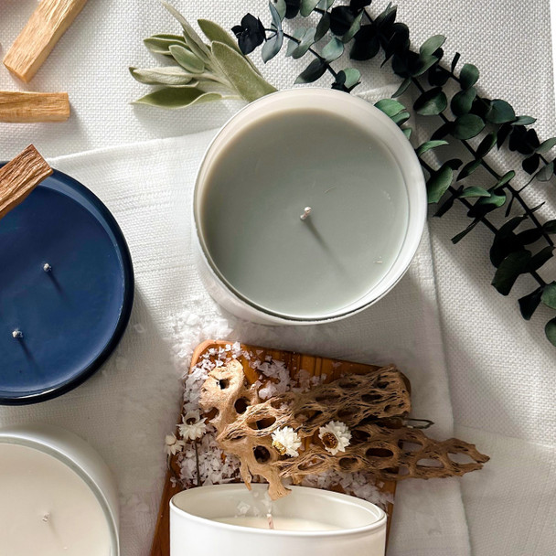 An artistic overhead shot of the Eucalyptus & Sage candle surrounded by fresh eucalyptus and sage leaves, highlighting the natural elements of its fragrance.