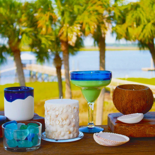 The Summer Days candle is styled in an outdoor, poolside setting along with other summer-themed candles, creating a relaxing and sunny vacation vibe.