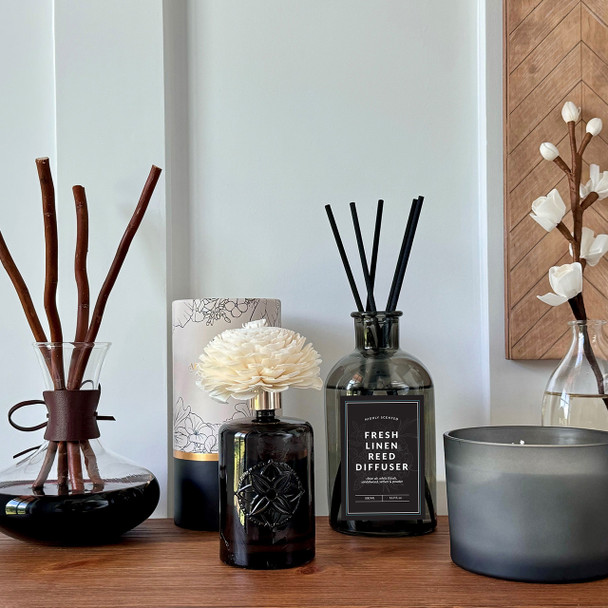 The reed diffuser is displayed as part of a larger home fragrance collection on a shelf, showing how it pairs with other decorative objects to enhance a room's ambiance.