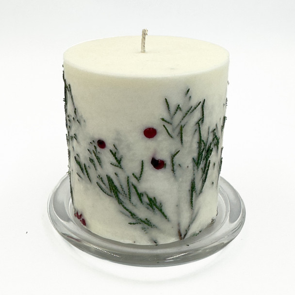 Close-up of Fir & Berry Inclusion Candle with embedded fir sprigs and red berries displayed on a small white plate