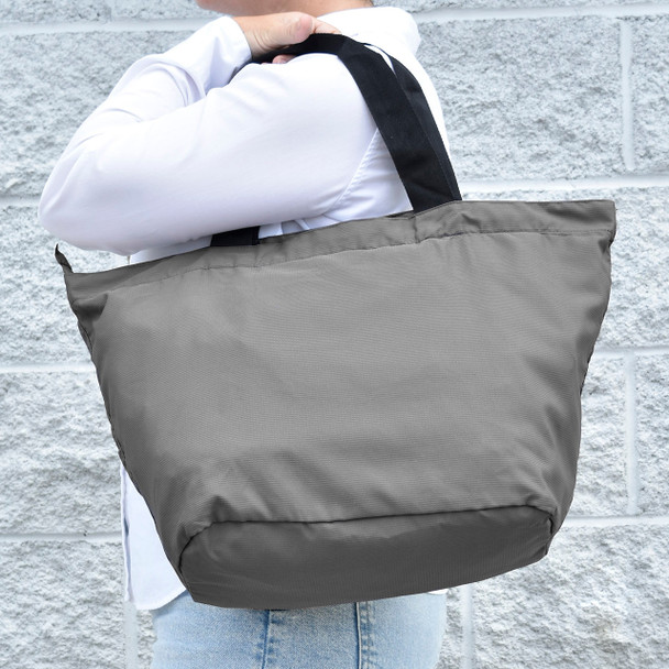 A person is shown carrying the lava gray tote bag over their shoulder at the beach, demonstrating its use as a spacious and durable beach bag.