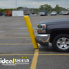 Yellow flexible safety post bending on impact as a pickup truck bumper makes contact in a parking lot