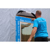 Contractor using a hand tool to press blue butyl flashing tape around a window header for a moisture-proof seal.