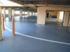 Freshly coated gray polyurethane deck coating applied to a covered parking garage floor.