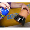 A person applies a black rubberized spray coating to the base of a terracotta flower pot.