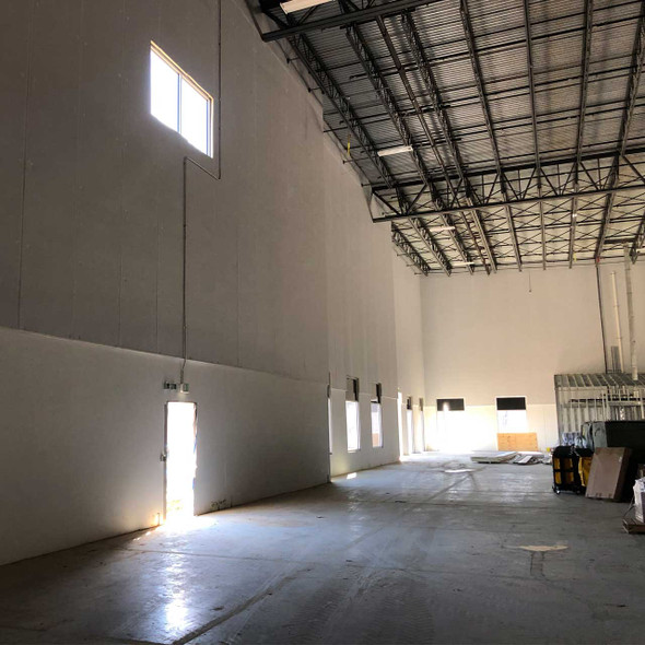 Air barrier membrane applied to high interior drywall partition in commercial building.