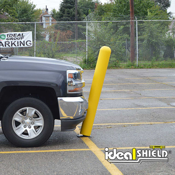 Pickup truck bumper contacting a yellow flexible safety post that bends on impact in a parking lot setting