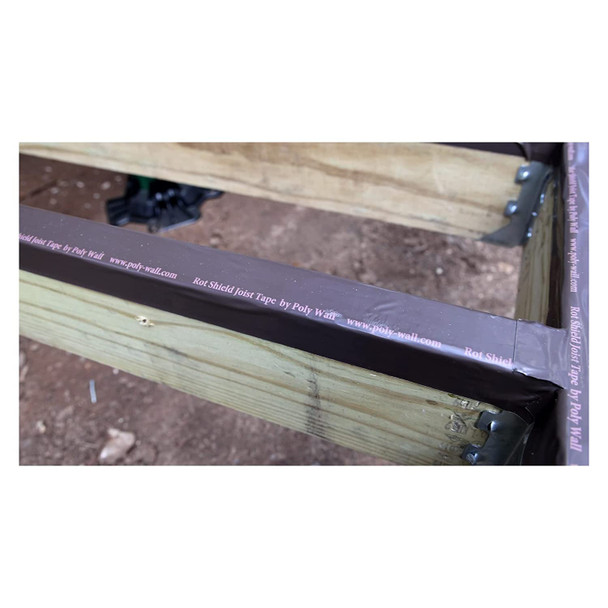 Close-up of brown joist tape applied to the top of a wooden deck joist to protect the lumber from moisture and rot.