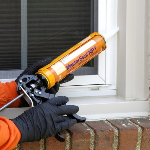 Contractor applying polyurethane sealant to a window perimeter joint with a caulking gun