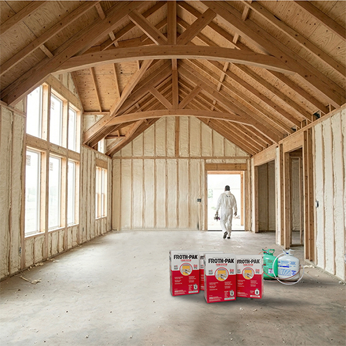Interior of unfinished wood-framed room with spray foam insulation applied between studs and exposed vaulted ceiling beams; worker exiting in protective suit with foam kits placed on the floor.